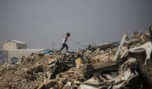 صبي فلسطيني يمشي وسط الأنقاض قرب مخيم للنازحين في منطقة النصيرات وسط غزة 28/6/2026 | وكالة الأنباء الفرنسية