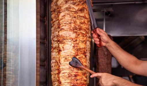 عامل يقطع من سيخ شاورما دجاج