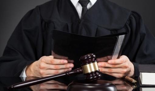 شخص يرتدي روب المحاماة وأمامه مطرقة القضاء
