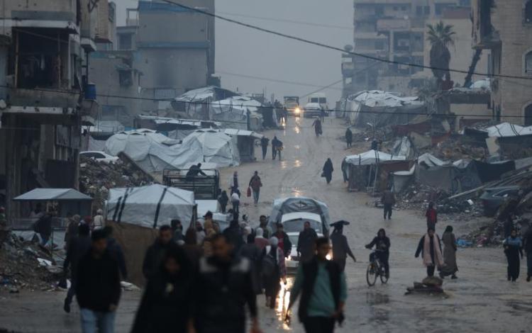 فلسطينيون يسيرون تحت المطر في ظروف إنسانية قاسية تعكس آثار حرب الإبادة الإسرائيلية على غزة