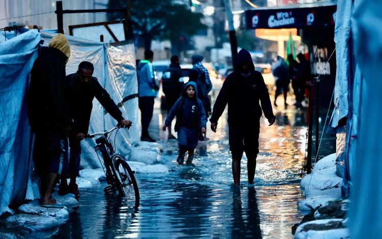 نازحون يمرون عبر برك المياه جراء الأمطار الغزيرة في مدينة غزة 15/12/2025 | وكالة الأنباء الفرنسية