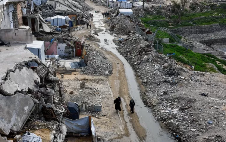 فلسطينيون يسيرون بين أنقاض المباني السكنية التي دمرتها حرب الإبادة الإسرائيلية في مدينة غزة 28/1/2026 | رويترز