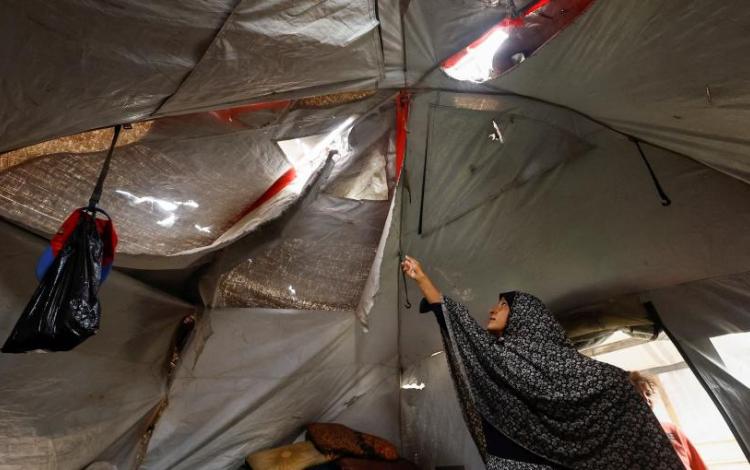 سيدة فلسطينية تعرض سقف خيمتها الممزق في أحد مخيمات النزوح في قطاع غزة | رويترز