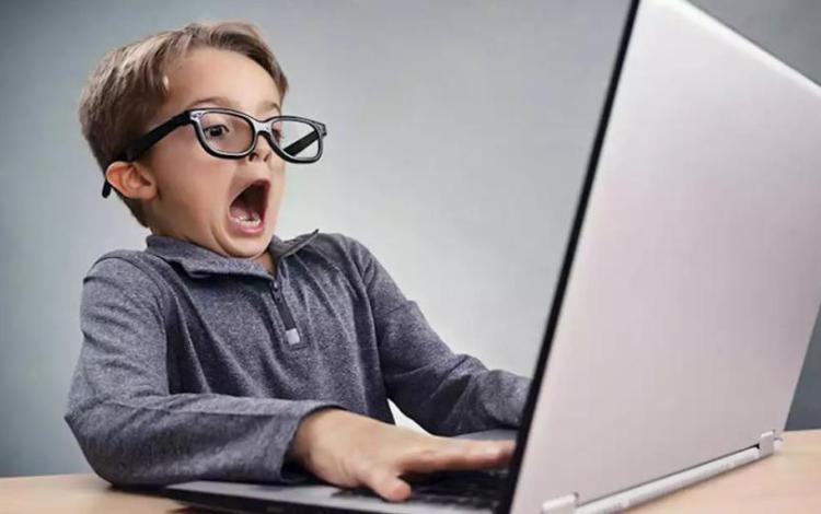 طفل يستخدم حاسوبا محمولا | تعبيرية