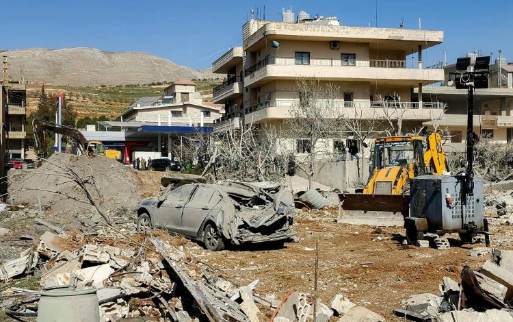 جرافة تزيل الأنقاض بالقرب من مبانٍ متضررة بشدة بقرية بدنايل بمنطقة سهل البقاع الشرقية في لبنان | وكالة الأنباء الفرنسية