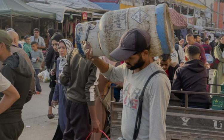 فلسطيني يحمل على كتفه أسطوانة غاز | وكالة الأنباء الفرنسية