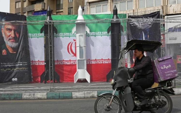 سائق دراجة نارية يمر بمحاذاة نماذج صواريخ إيرانية نصبت على جانب الطريق في طهران | وكالة الأنباء الفرنسية