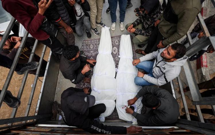 فلسطينيون بجوار جثماني شهيدين إثر غارة إسرائيلية على غزة 26/2/2026 | رويترز