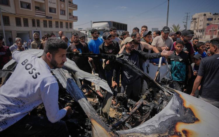 فلسطينيون يتفقدون مركبة استهدفت بغارة جوية إسرائيلية في دير البلح وسط قطاع غزة | أسوشييتد برس