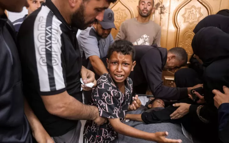 طفل فلسطيني بجوار جثمان شقيقه الذي استشهد بغارة إسرائيلية في خانيونس جنوب غزة 24/6/2026 | وكالة الأنباء الفرنسية