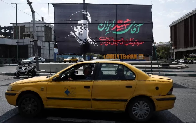 سيارة أجرة تمر أمام لافتة تحمل صورة المرشد الإيراني السابق علي خامنئي قبيل جنازته في طهران | رويترز