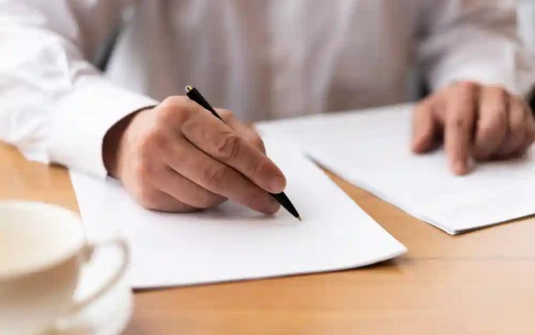 شخص يمسك بقلم ويتهيأ للتوقيع